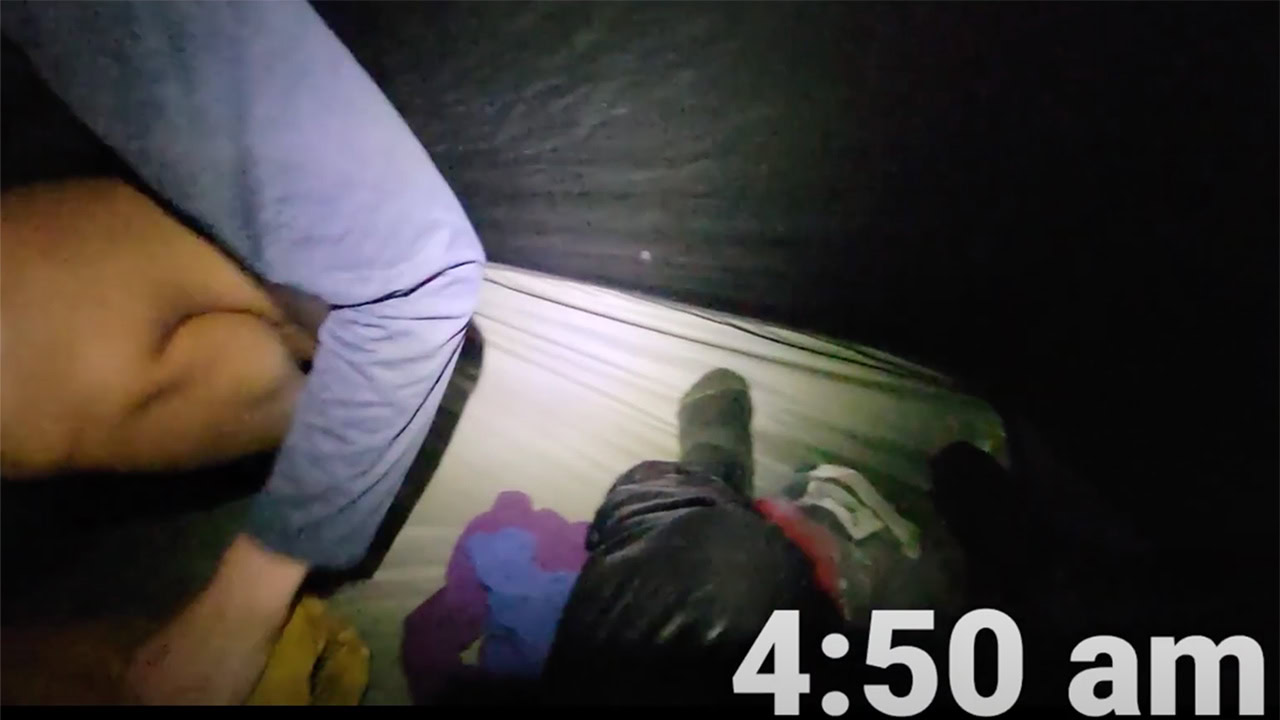 Two people pack up their stuff inside of a tent