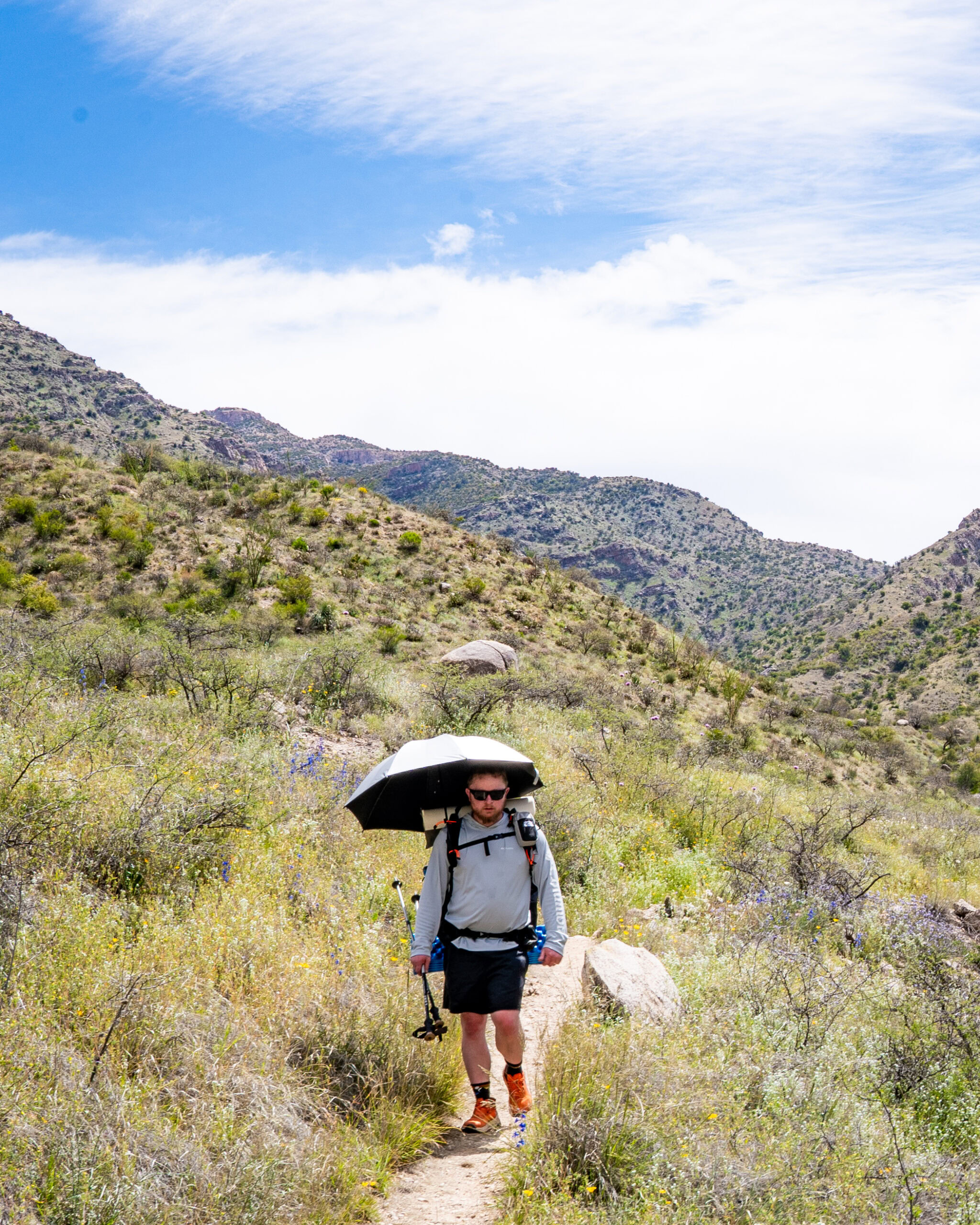 A man walks with a sun umbrella outside.