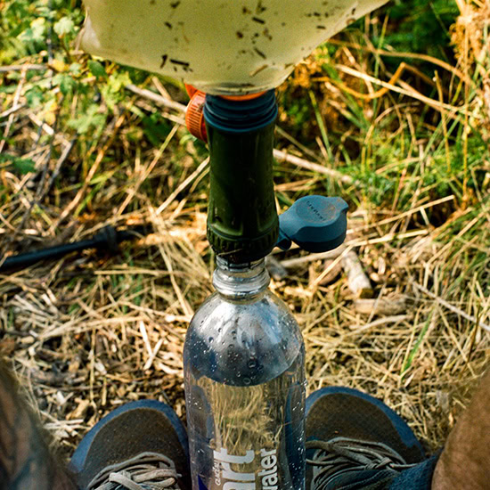 A man uses a water filter on trail