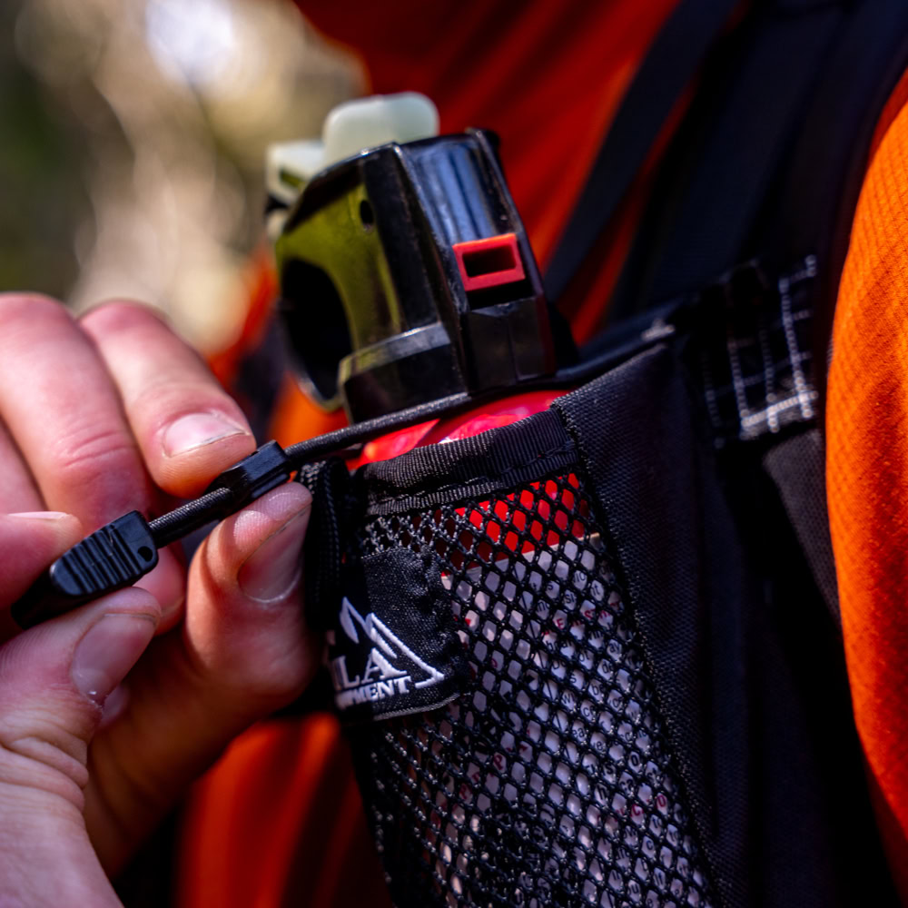 A backpacker loosens the holder strap on the ULA Deploy.